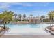Community pool featuring a walk in access area, rock waterfall, lush palms, and lounge chairs at 8972 Coco Palm Rd, Kissimmee, FL 34747