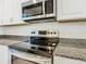 Modern kitchen showcasing stainless steel appliances, granite countertops, and white cabinetry at 9432 Komika Ln, Winter Garden, FL 34787