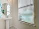 The powder room has a pedestal sink, round mirror, and a window with privacy blinds at 9432 Komika Ln, Winter Garden, FL 34787