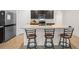 The kitchen features stainless steel appliances, dark wood cabinets, and a breakfast bar with three stools at 1059 Cypress Fox Blvd, Davenport, FL 33897