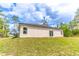 Sloped backyard featuring a home with beige stucco, sliding glass doors, and various windows at 13 Oak Trail Pl, Ocala, FL 34472