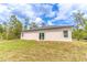 Side view of a home's backyard with beige stucco, sliding glass doors, and native trees at 13 Oak Trail Pl, Ocala, FL 34472