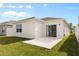 A simple backyard with a concrete patio and a well-maintained lawn with a sliding glass door at 1580 Eucalyptus Way, Davenport, FL 33837