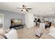 Comfortable living room with tile floors, neutral paint, ceiling fan, TV, and an open flow into the kitchen and dining area at 1580 Eucalyptus Way, Davenport, FL 33837