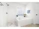 Bright bathroom features a separate shower and soaking tub, all finished with elegant white tile and fixtures at 1624 Malcolm Pointe Dr, Winter Garden, FL 34787