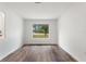Bright living room featuring wood-look floors, modern paneling, and a large window overlooking a green space at 16336 Old Cheney Hwy, Orlando, FL 32833