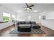 Open living room with hardwood floors, a large sectional and a workspace near bright windows at 1802 Candlenut Cir, Apopka, FL 32712