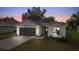 Charming single-story home with a well-manicured lawn and a two-car garage at dusk at 2132 Pine Meadows Golf Course Rd, Eustis, FL 32726