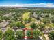 Aerial view of a home with a golf course in the background, featuring mature trees and solar panels at 2409 Twickingham Ct, Clermont, FL 34711