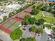 Aerial view of multiple tennis courts surrounded by trees with a parking lot for easy access at 2409 Twickingham Ct, Clermont, FL 34711
