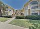 Inviting two-story condo featuring yellow siding, brick accents, and manicured landscaping at 2442 Sweetwater Club Cir # 43, Kissimmee, FL 34746
