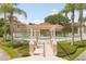 Community pool area, showcasing a gated entrance, a pergola, and lush landscaping with palm trees at 2808 Osprey Cove Pl # 201, Kissimmee, FL 34746