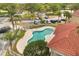 Aerial view of the kidney-shaped community pool, with surrounding palm trees, parking and red-tile roof at 2808 Osprey Cove Pl # 201, Kissimmee, FL 34746