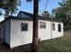 Exterior of a modest white house with dark trim and mature trees in a grassy yard at 3772 Cochran St, Apopka, FL 32703