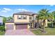 Stunning two-story home featuring a brick driveway, three-car garage, and manicured lawn with a palm tree at 427 Egret Place Dr, Winter Garden, FL 34787