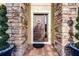 Charming front door with decorative wreath, brick surround, and lush greenery in decorative pots at 427 Egret Place Dr, Winter Garden, FL 34787