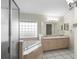 Bright bathroom featuring a double vanity, a glass-block window, a soaking tub, and a separate shower at 453 Kettering Rd, Deltona, FL 32725