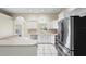 Well-lit kitchen featuring stainless steel appliances, white cabinets, and an archway leading to another room at 453 Kettering Rd, Deltona, FL 32725