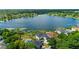 Aerial view features a home with a backyard pool, lake, and mature trees at 5112 Jetsail Dr, Orlando, FL 32812