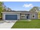 Charming single-story home with a gray exterior, blue door and garage door, and a well-manicured green lawn at 75 Guava Ter, Ocklawaha, FL 32179