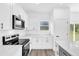 Modern kitchen features stainless steel appliances, white cabinets, granite countertops, and backyard views through a window at 75 Guava Ter, Ocklawaha, FL 32179