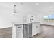 Open-concept kitchen features white cabinets, an island with stainless dishwasher, and a modern faucet at 75 Guava Ter, Ocklawaha, FL 32179