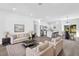 Open-concept living space with wood floors, a modern sofa set, and a kitchen with stainless steel appliances at 75 Guava Ter, Ocklawaha, FL 32179