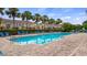 Community pool surrounded by palm trees, lounge chairs, and brick patio with nearby townhomes at 7660 Ripplepointe Way, Windermere, FL 34786