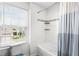 This bathroom features a shower-tub combo with white tile and a window providing natural light at 812 Marcel Loop, Davenport, FL 33837
