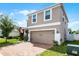 Two-story home with brick driveway, attached garage and an American flag at 812 Marcel Loop, Davenport, FL 33837