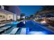Night view of a backyard pool with a hot tub, lounge chairs in the water, and outdoor seating area at 8638 Finsen St, Orlando, FL 32827