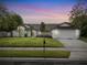 Charming single-story home with well-manicured lawn, lush trees, and a beautiful twilight sky at 1012 Willa Lake Cir, Oviedo, FL 32765