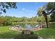 Picturesque lake surrounded by lush greenery, a welcoming entrance sign, and stone accents at 102 Fairway Dr # 102, Longwood, FL 32779