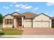 Charming single-story home featuring a manicured lawn, brick driveway, and a two-car garage at 1199 Playa Del Sol Ln, St Cloud, FL 34771