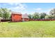 Spacious backyard with lush green grass and a red wooden fence under a bright blue sky at 12030 Kirby Smith Rd, Orlando, FL 32832
