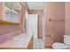 Bathroom with pink walls and sink, a mirror, a sink, a toilet, and a shower with tiled flooring at 12030 Kirby Smith Rd, Orlando, FL 32832