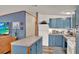 Compact kitchen featuring blue cabinetry and white appliances, with a view of the living room at 133 Moss Dr, Debary, FL 32713