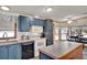 Efficient kitchen layout with blue cabinetry, white appliances, and a center island next to dining area at 133 Moss Dr, Debary, FL 32713