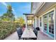 Back patio with a dining table with chairs, manicured bushes, and light blue doors at 13618 Briand Ave, Orlando, FL 32827