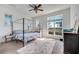 Bright bedroom features a four-poster bed, ceiling fan, plush rug, and view of trees at 13618 Briand Ave, Orlando, FL 32827