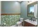 Stylish powder room features a modern vanity, decorative mirror, and tropical wallpaper accent wall at 2004 Fleming Mist Pl, Kissimmee, FL 34747
