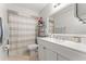 Bright bathroom features a modern vanity with a white countertop, large mirror, and neutral-toned shower curtain at 211 Dalton Dr, Kissimmee, FL 34758