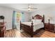 Charming bedroom features a statement dark wood bed frame, hardwood floors, and a ceiling fan at 211 Dalton Dr, Kissimmee, FL 34758