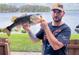 Personal holding a large bass fish in front of a lake and green lawn at 222 Georgetown Dr # C, Casselberry, FL 32707