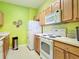 A view of the kitchen with white appliances, wood cabinets, and a bright green color scheme at 2781 Almaton Loop # 404, Kissimmee, FL 34747