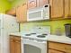 Bright kitchen featuring white appliances, wood cabinets, and ample counter space for food preparation at 2781 Almaton Loop # 404, Kissimmee, FL 34747