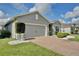 View of the home's garage and landscaping featuring a brick driveway and manicured trees at 299 Whirlaway Dr, Davenport, FL 33837