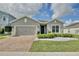Charming single-story home with a brick driveway, manicured landscaping, and a gray stucco exterior at 299 Whirlaway Dr, Davenport, FL 33837