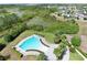 Aerial view of the pool area with a large, modern pool, lush landscaping, and view of the surrounding community and pond at 299 Whirlaway Dr, Davenport, FL 33837