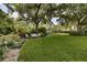 Lush backyard with a charming bench seating area, surrounded by mature trees and meticulous landscaping at 320 Mary Jess Rd, Orlando, FL 32839